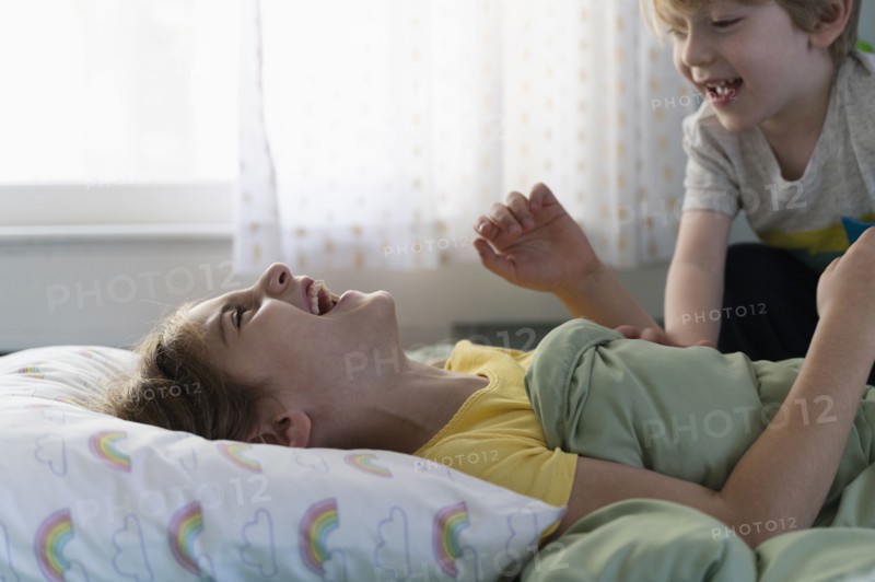 Brother (6-7) and sister (8-9) playing on bed