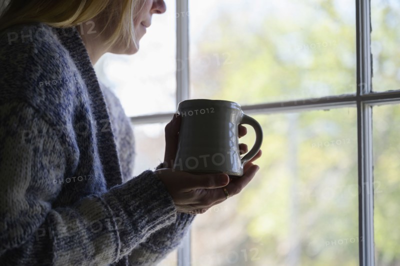 Woman holding mug and looking out window