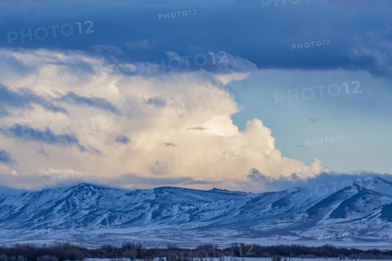 Snow dusted mountains and clouds over prairie