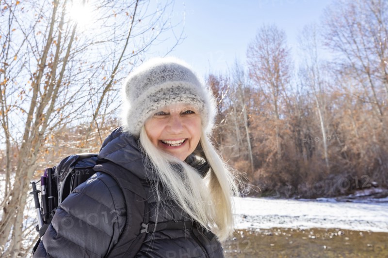 Winter portrait of smiling woman hiking along river