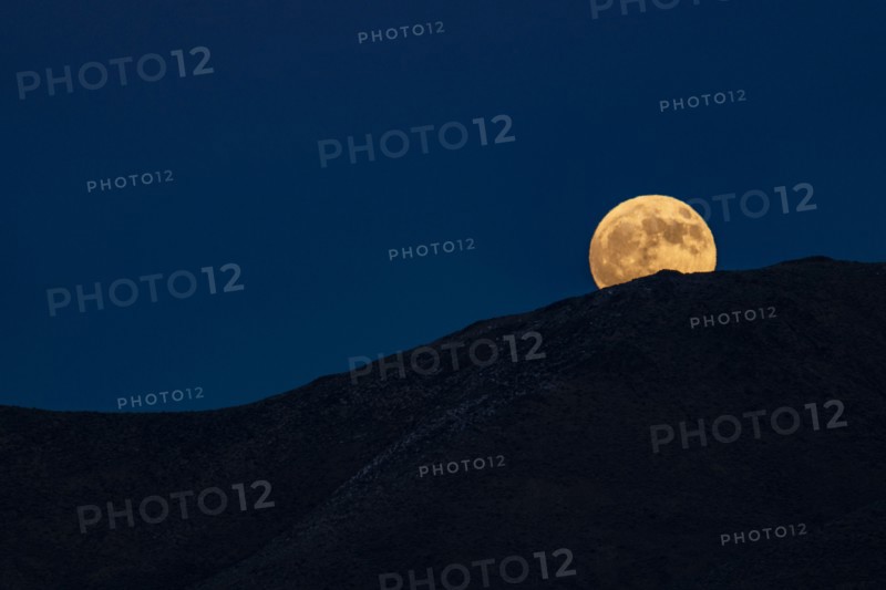Full moon rising over hills