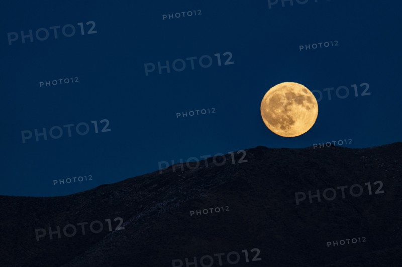 Full moon rising over hills