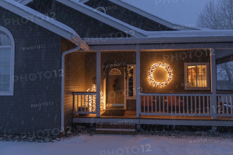 Porch decorated with Christmas lights during snow storm