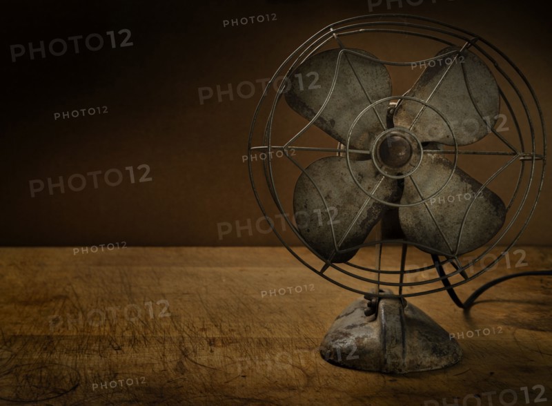 Old metal electric fan on wooden table