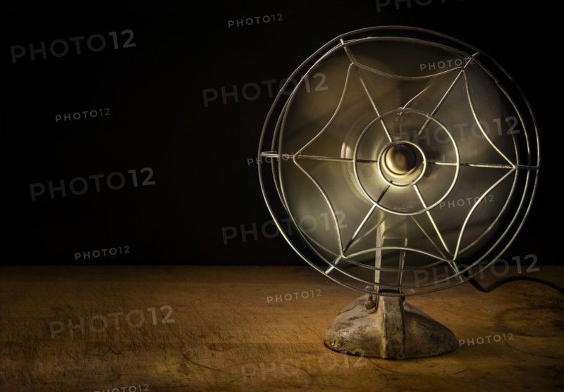 Old metal electric fan on wooden table