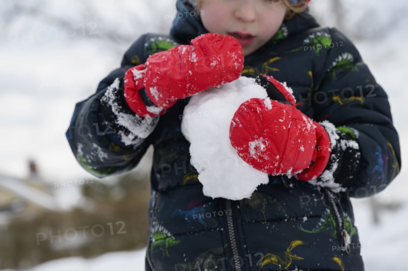 Boy (6-7) holding snowball