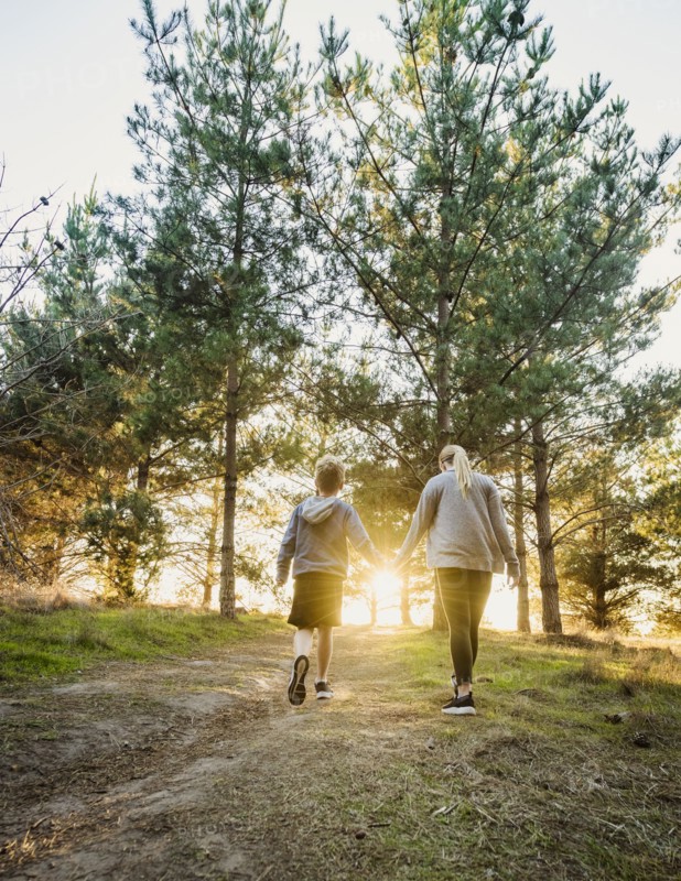 Rear view of boy and girl holding hands and walking in landscape at sunset