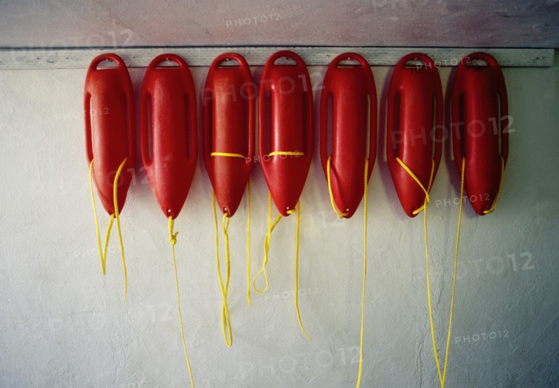 Row of red lifeguard floats hanging on wall