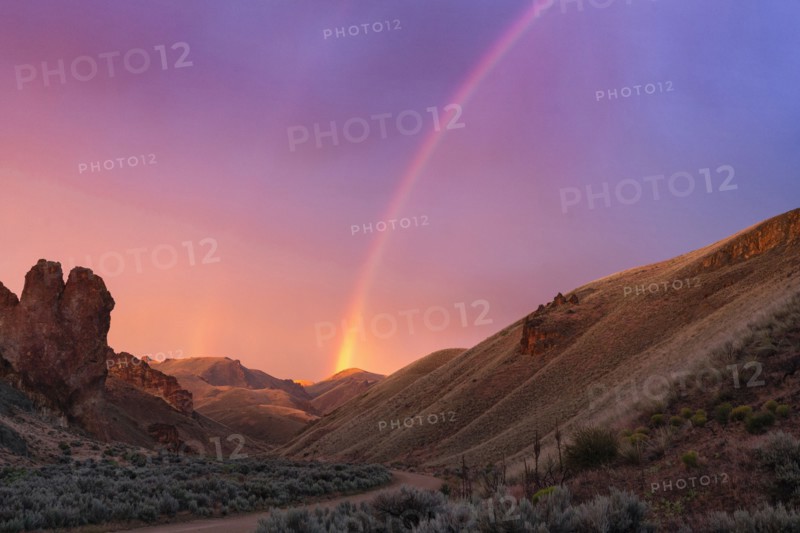 Rainbow above desert landscape at sunset