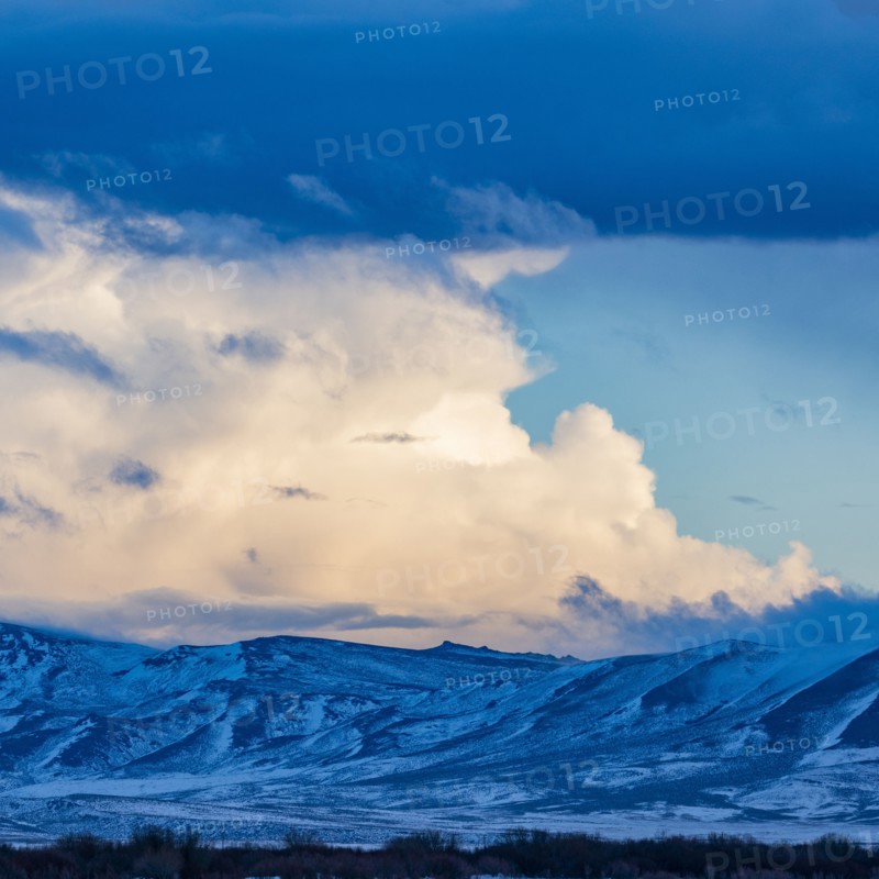 Snow dusted mountains and clouds over prairie
