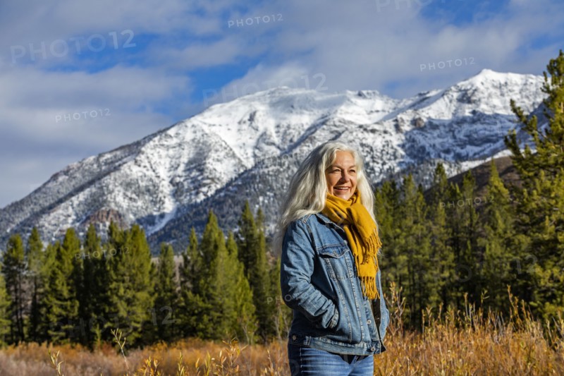 Smiling senior woman standing in autumn mountain landscape