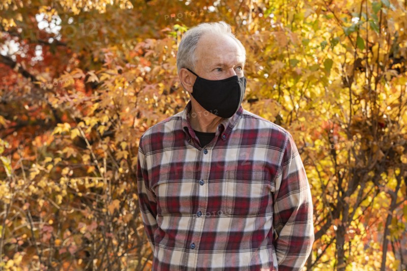 Senior man wearing protective mask in autumn park