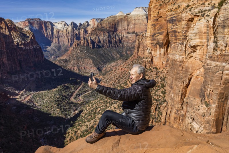 Senior man using phone at overlook of Zion Canyon in Zion National Park
