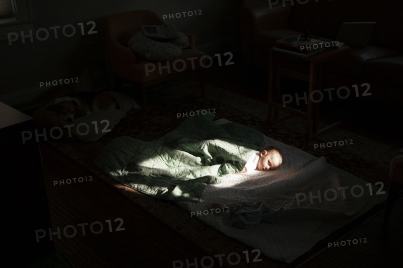 Baby boy sleeping in sunspot in bedroom
