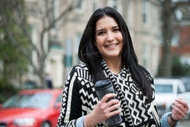 Young woman carrying travel mug