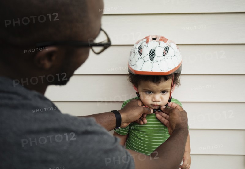 Father putting on helmet for son