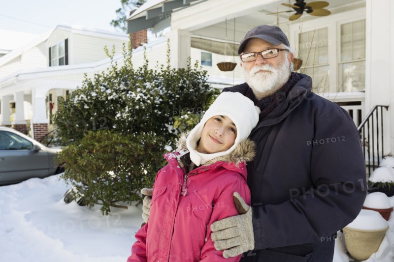 Grandfather and granddaughter outside house in winter