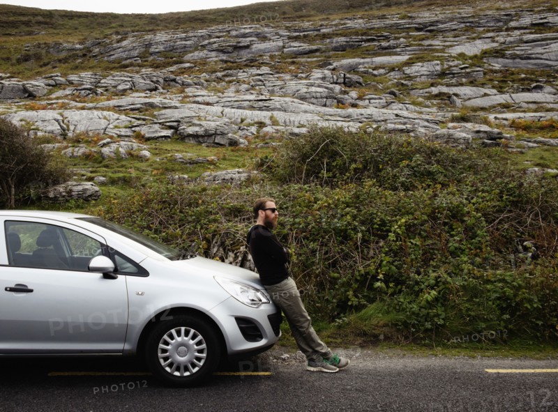 Mid adult man leaning against car bonnet