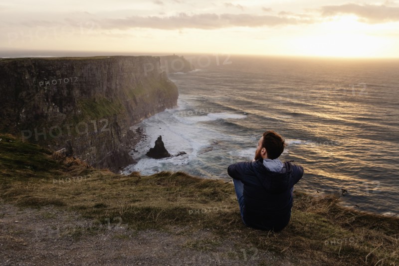Mid adult man sitting on The Cliffs of Moher