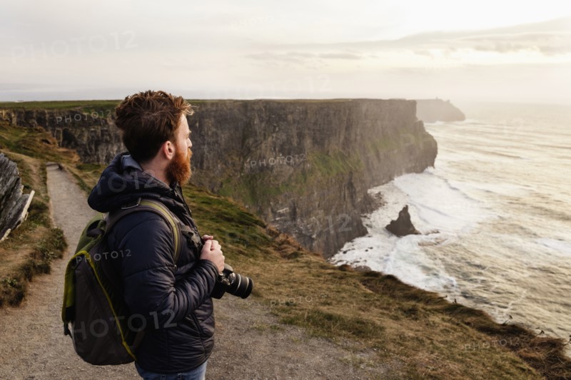 Mid adult man on The Cliffs of Moher with camera