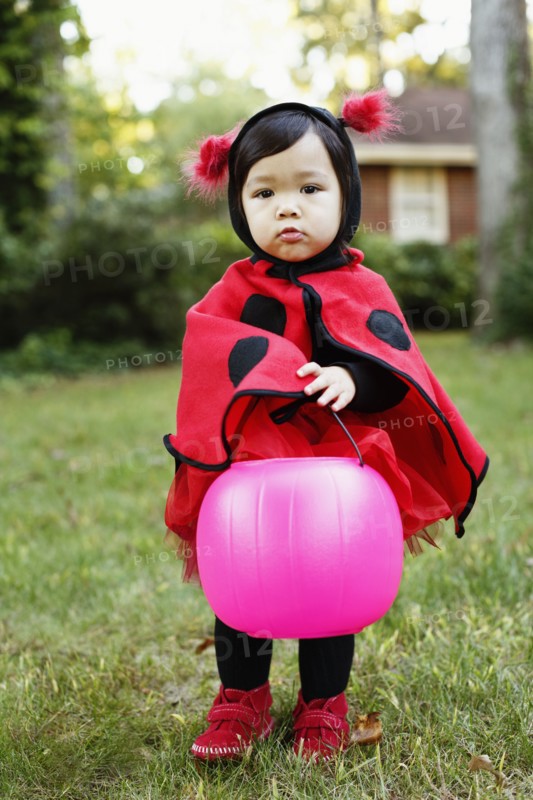 Young girl dressed up as ladybird with trick or treat bucket