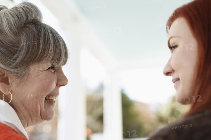Close up of senior woman and adult daughter laughing on porch