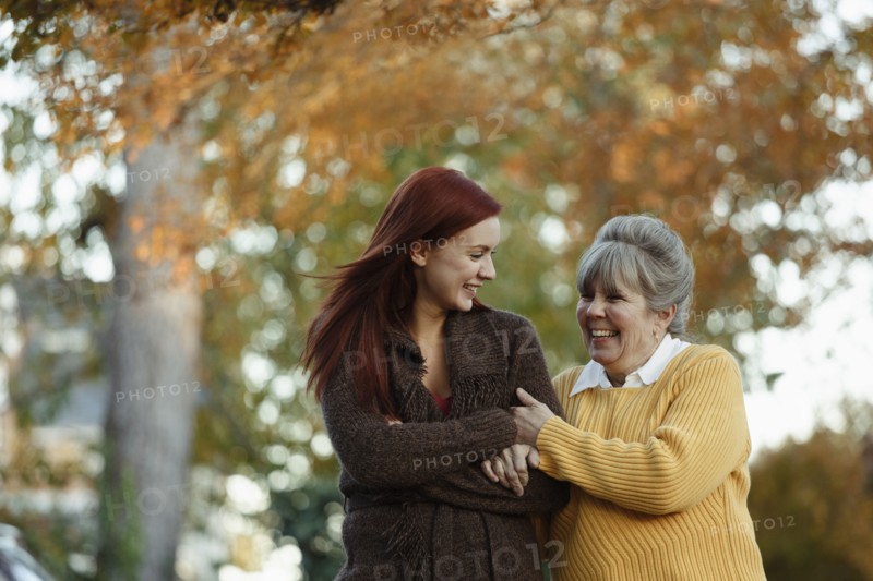 Senior woman and adult daughter strolling in suburban park