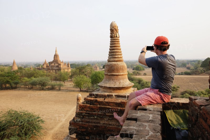 Man taking photograph from stone wall