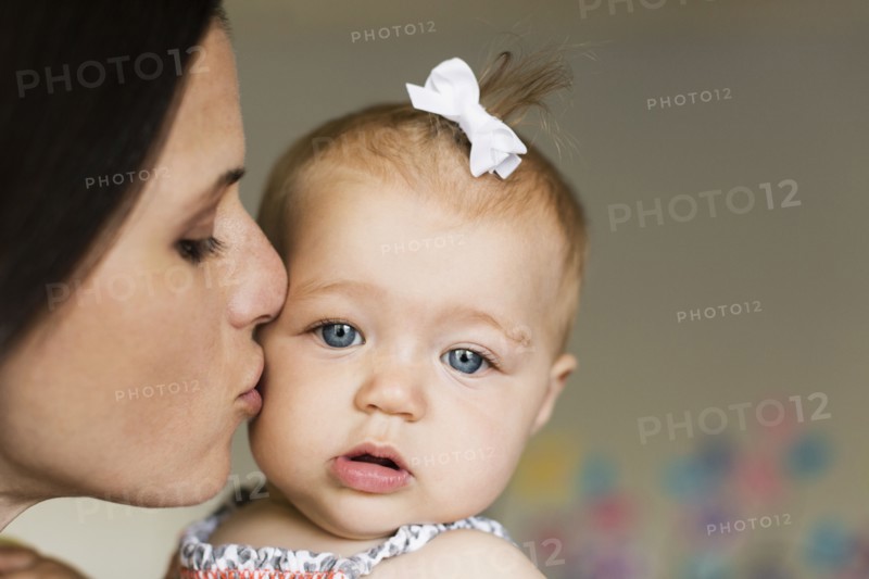 Close up of mid adult mother kissing baby daughter on cheek