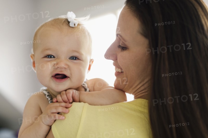 Over the shoulder portrait view of happy baby girl and mid adult mother