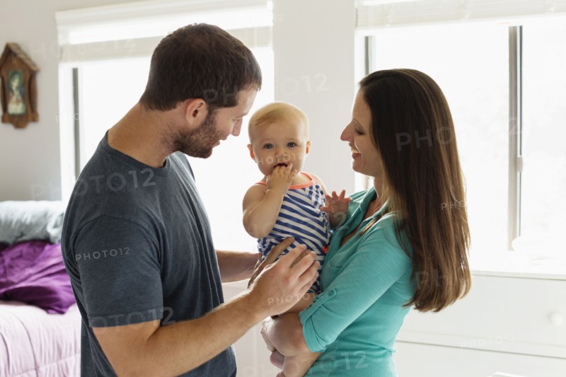 Portrait of mid adult couple with baby daughter in bedroom