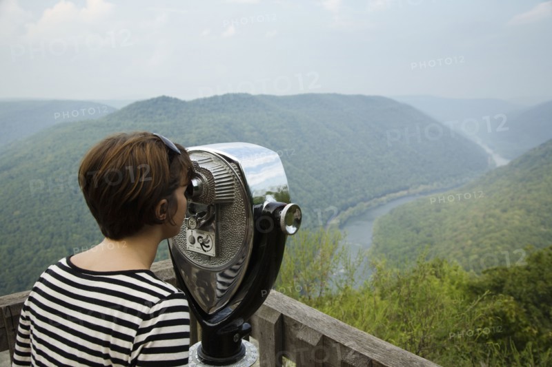 Mid adult woman looking through coin operated binoculars