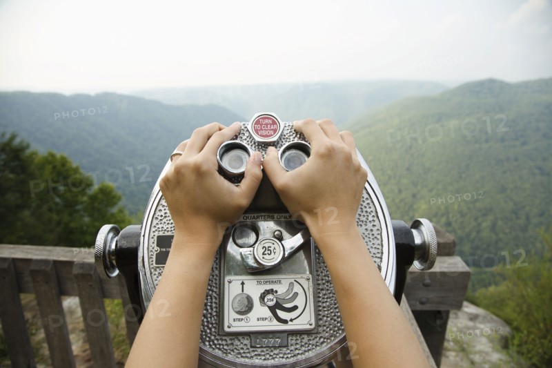 Mid adult woman holding coin operated binoculars