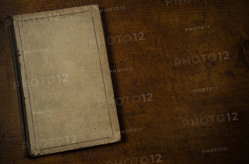 Old book with blank cover resting on old wooden desk top