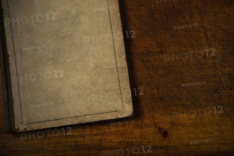 Old book with blank cover resting on old wooden desk top