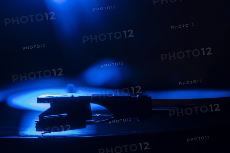 Close-up of a record player needle on record in blue light