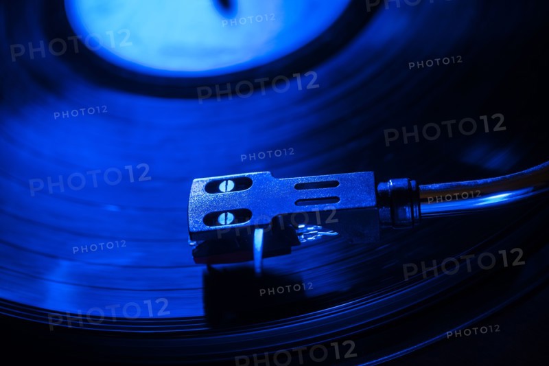 Close-up of a record player needle on record in blue light