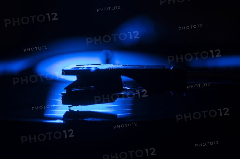Close-up of a record player needle on record in blue light