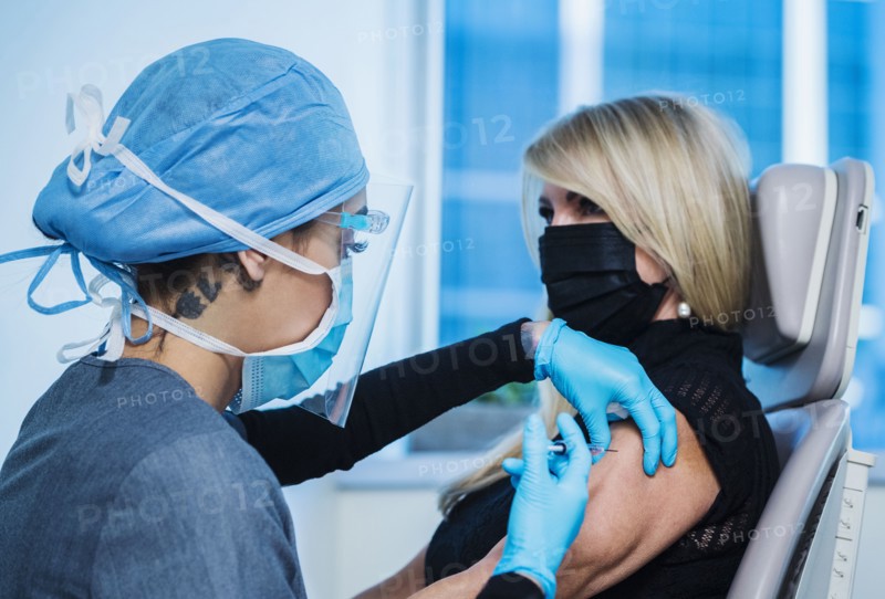 Woman in face mask receiving Covid-19 vaccination