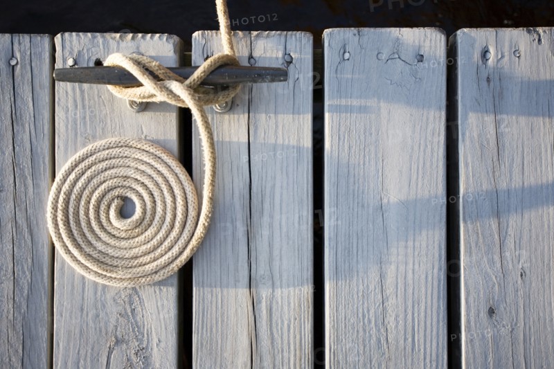 Overhead view of coiled rope tied around bollard
