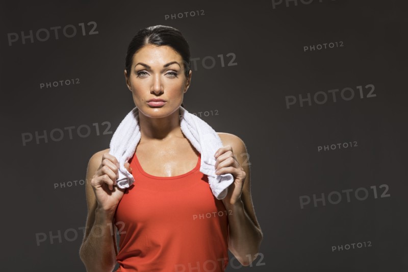 Studio portrait of athletic woman in red sleeveless top holding towel