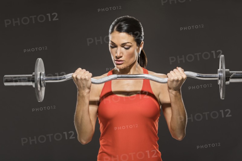Athletic woman in red sleeveless top weight training