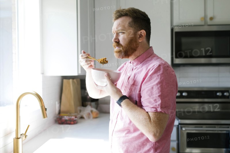 Man eating cereal in kitchen