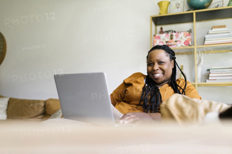 Smiling woman sitting on sofa and working on laptop