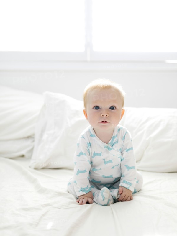Baby boy sitting on bed