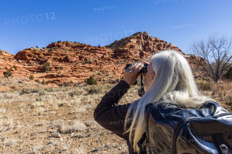 Woman using binoculars while hiking in Grand Staircase-Escalante National Monument