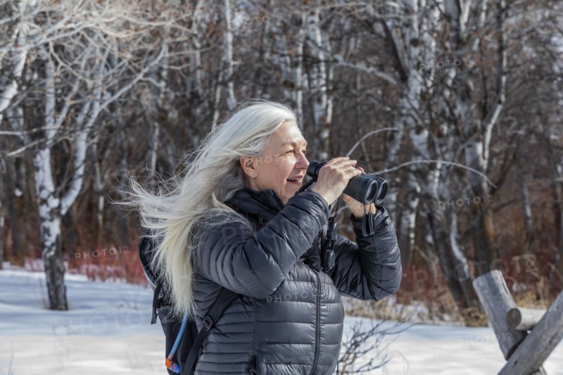 Senior woman using binoculars while hiking