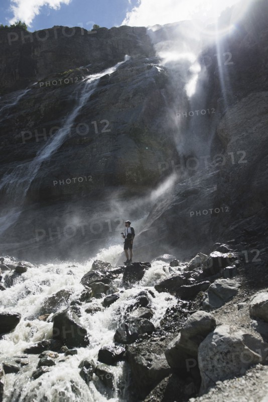Man standing near Sofiyskiye Vodopady waterfall in Caucasus Mountains