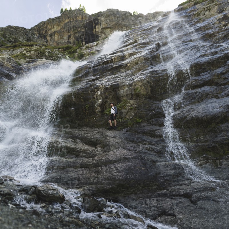 Man standing near Sofiyskiye Vodopady waterfall in Caucasus Mountains