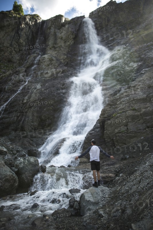 Man standing near Sofiyskiye Vodopady waterfall in Caucasus Mountains